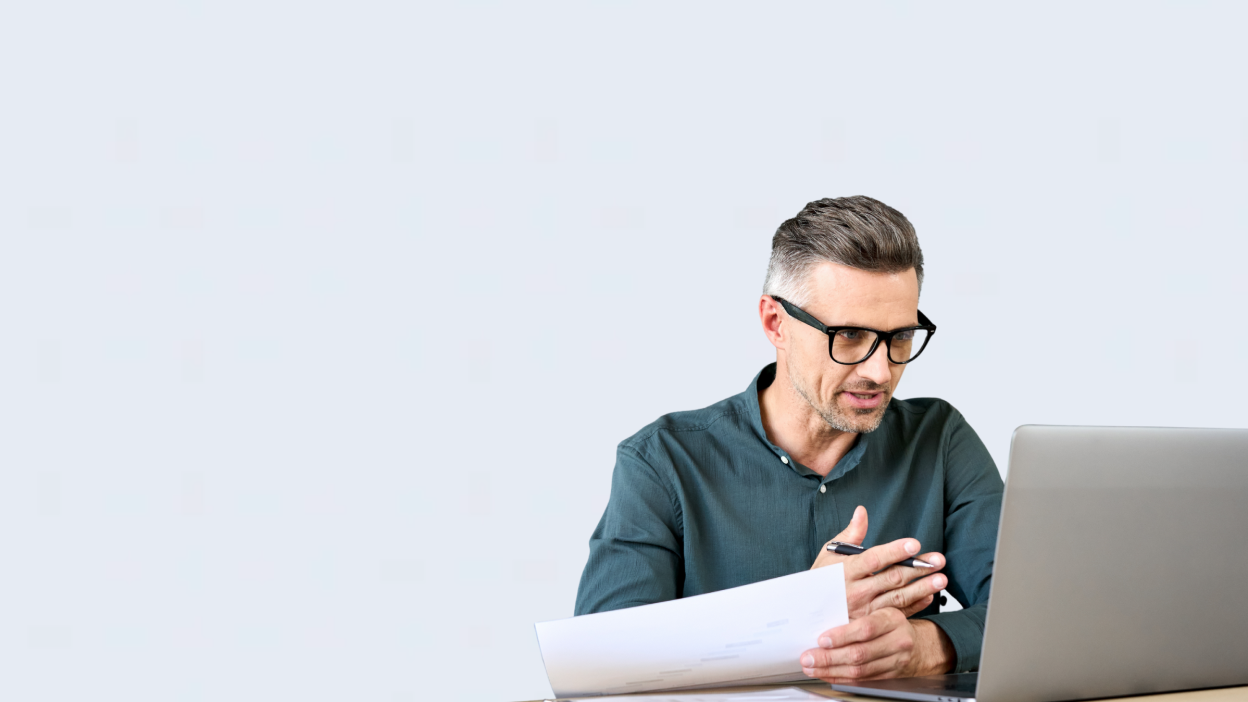 Mann mit Brille arbeitet am Laptop und hält Unterlagen