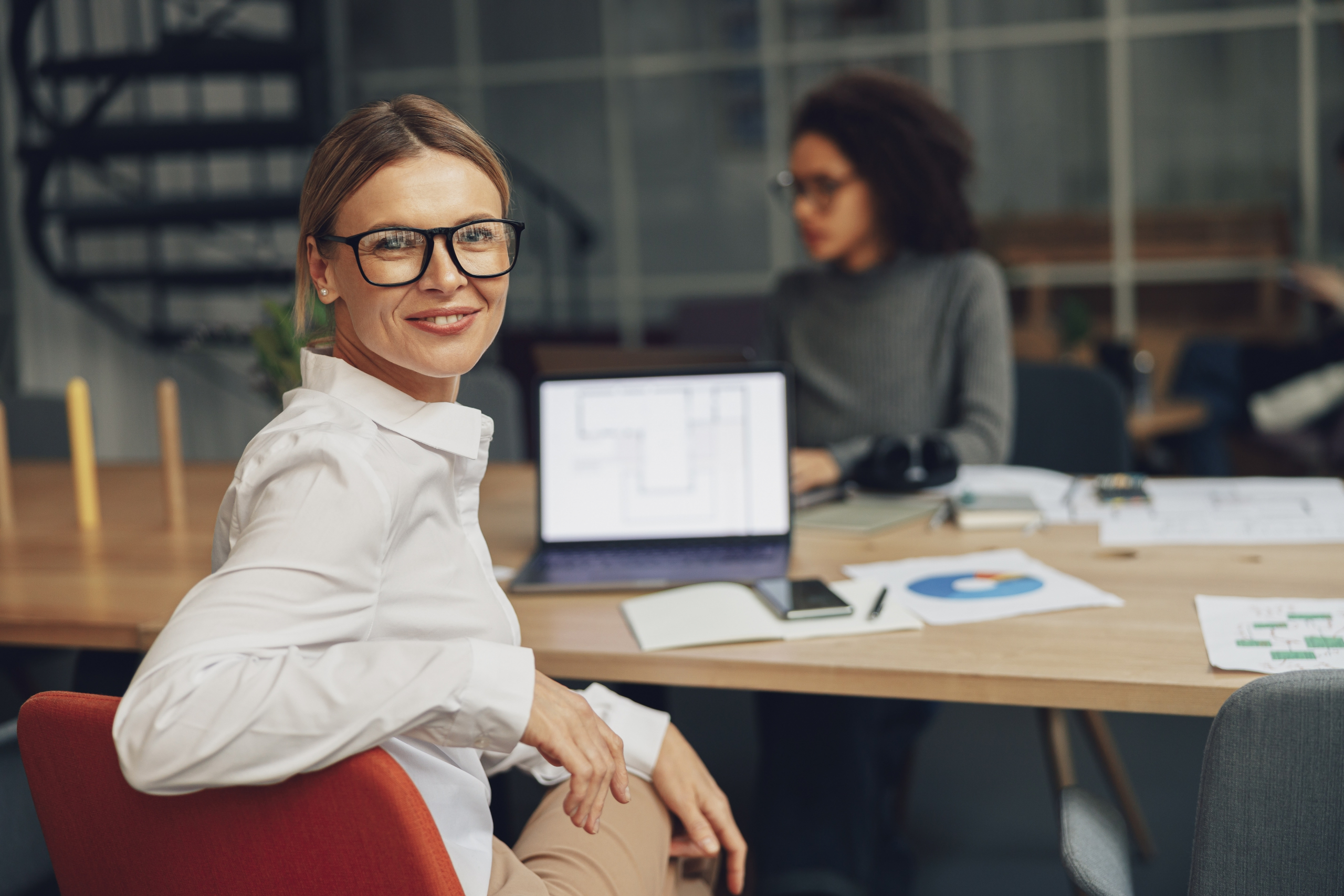 HR-Mitarbeiterin sitzt im Büro und arbeitet an Laptop und Recruiting-Unterlagen im Team