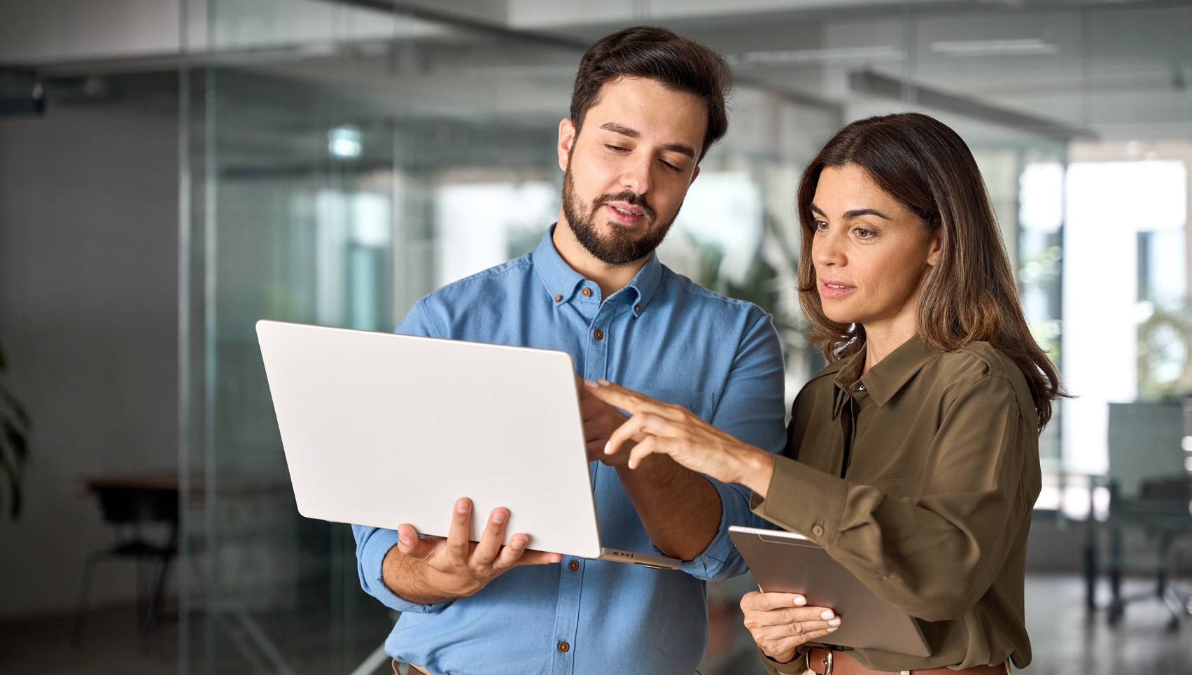 Mann und Frau analysieren gemeinsam Daten auf einem Laptop im modernen Büro