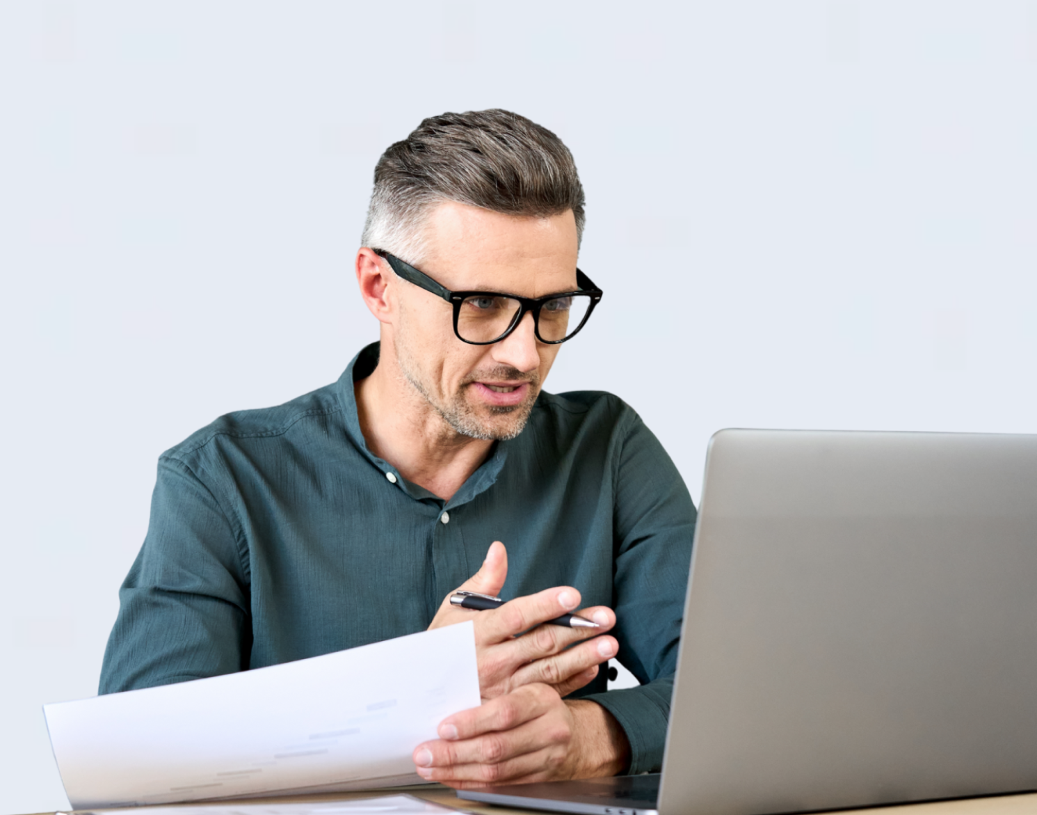 Mann mit Brille arbeitet am Laptop und hält Unterlagen